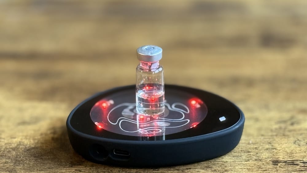 Nick's Glowing IC Pad 3 glowing red with a BPC-157 peptide vial on top of it